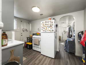 Kitchen with dark hardwood / wood-style flooring and white appliances