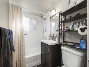 Full bathroom with vanity, a healthy amount of sunlight, toilet, and shower / bathtub combination with curtain