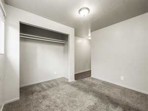 Unfurnished bedroom featuring carpet flooring, a textured ceiling, and a closet