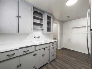 Kitchen with white cabinets, dark wood-type flooring, and sink