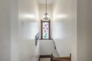 Stairway with carpet floors and an inviting chandelier