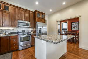 Kitchen featuring light stone counters, a center island, dark hardwood / wood-style floors, and appliances with stainless steel finishes