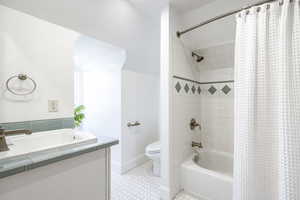 Bathroom with tile patterned floors, toilet, and shower / tub combo with curtain