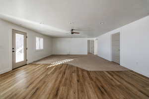 Unfurnished living room with hardwood / wood-style floors, a textured ceiling, and ceiling fan