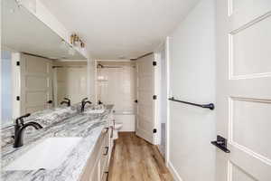 Full bathroom with hardwood / wood-style floors, vanity, shower / bathtub combination, and a textured ceiling