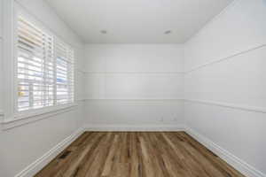 Empty room/office with dark hardwood / wood-style floors and ornamental molding