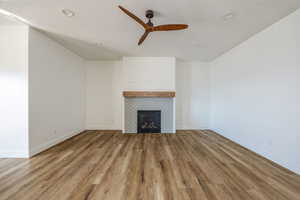 Unfurnished living room with a tile fireplace, ceiling fan, and light hardwood / wood-style floors