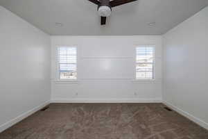 Spare room with plenty of natural light, medium colored carpet, and ceiling fan