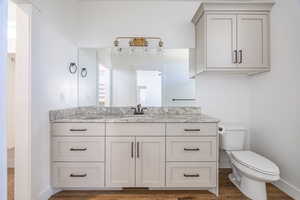 Bathroom with toilet, vanity, and hardwood / wood-style flooring