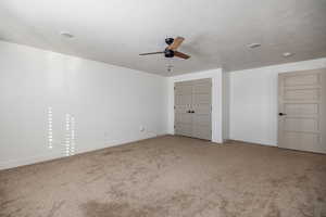 Unfurnished bedroom featuring carpet flooring, ceiling fan, a textured ceiling, and a closet