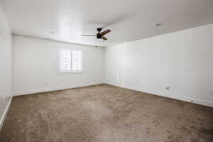 Empty room featuring carpet flooring, a textured ceiling, and ceiling fan