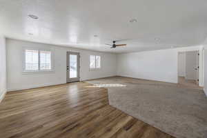 Unfurnished living room with ceiling fan, a textured ceiling, and light wood-type flooring