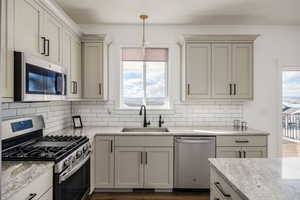 Kitchen with pendant lighting, sink, stainless steel appliances, and a wealth of natural light