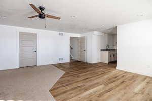 Unfurnished living room with a textured ceiling, light hardwood / wood-style floors, and ceiling fan