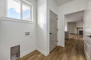 Clothes washing area featuring hookup for a washing machine, ceiling fan, a fireplace, and hardwood / wood-style flooring