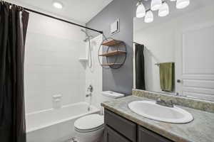 Full bathroom featuring shower / bath combination with curtain, vanity, and toilet