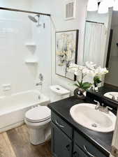 Full bathroom featuring toilet, hardwood / wood-style flooring, shower / tub combo with curtain, and vanity