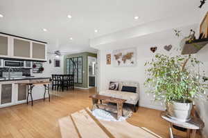 Living room with ceiling fan, light hardwood / wood-style floors, and sink