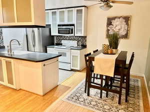 Kitchen with electric range, light wood-type flooring, ceiling fan, sink, and tasteful backsplash