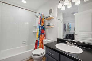 Full bathroom featuring vanity, toilet, and shower / bathtub combination with curtain