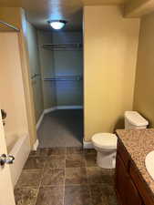 Bathroom with tile patterned floors, vanity, toilet, and a textured ceiling