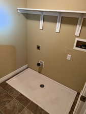 Laundry area with electric dryer hookup, dark tile patterned floors, and hookup for a washing machine