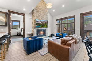 Living room featuring light hardwood / wood-style floors, a fireplace, a wealth of natural light, and vaulted ceiling