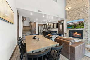 Dining space featuring light hardwood / wood-style floors, sink, a fireplace, and a high ceiling