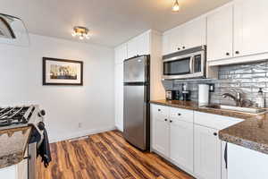 Kitchen featuring sink, white cabinets, dark wood-type flooring, and appliances with stainless steel finishes