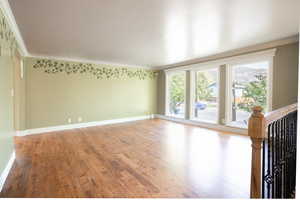 Empty room with hardwood / wood-style flooring and crown molding