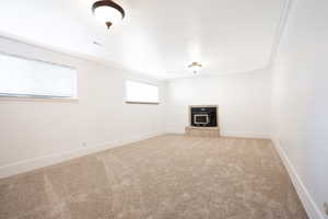 Unfurnished living room featuring carpet flooring, a wood stove, and crown molding