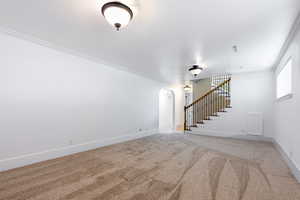 Unfurnished living room featuring carpet flooring and crown molding