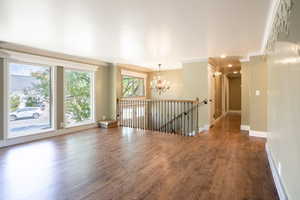 Spare room with a chandelier, dark hardwood / wood-style floors, and ornamental molding