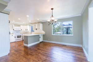 Kitchen featuring white cabinets, white appliances, kitchen peninsula, and dark wood-type flooring