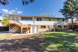 Back of property with central AC, a yard, and a wooden deck