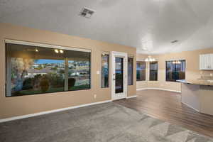 Unfurnished living room featuring a notable chandelier, dark hardwood / wood-style floors, and a textured ceiling