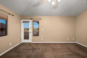 Unfurnished room featuring dark colored carpet, ceiling fan, a textured ceiling, and vaulted ceiling