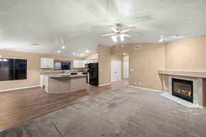 Unfurnished living room with hardwood / wood-style floors, a textured ceiling, and lofted ceiling