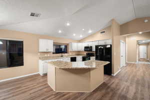 Kitchen with a center island, hardwood / wood-style flooring, white cabinetry, and black appliances