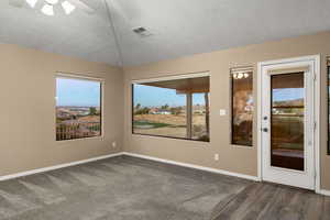 Spare room featuring a textured ceiling, ceiling fan, and dark wood-type flooring