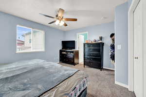 Carpeted bedroom featuring ceiling fan and a textured ceiling