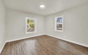 Empty room with hardwood / wood-style flooring and plenty of natural light