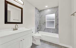 Full bathroom with tile patterned floors, toilet, vanity, and tiled shower / bath