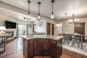 Kitchen featuring pendant lighting, a kitchen island, dark hardwood / wood-style flooring, and light stone countertops