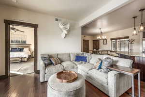 Living room featuring dark wood-type flooring and ceiling fan with notable chandelier