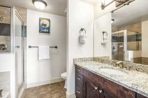 Bathroom featuring tile patterned flooring, vanity, a shower with door, and toilet