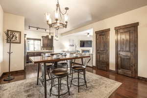 Dining room featuring ceiling fan with notable chandelier and dark hardwood / wood-style flooring