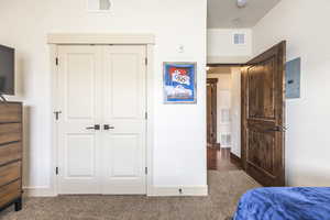 Bedroom with dark colored carpet, electric panel, and a closet