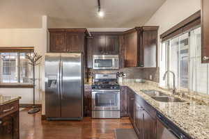 Kitchen with dark hardwood / wood-style flooring, sink, decorative backsplash, and stainless steel appliances