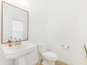 Bathroom with toilet, wood-type flooring, and sink